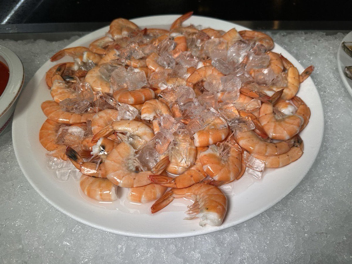 Peeled shrimp, served cold. A platter of peeled chilled shrimp resting on crushed ice