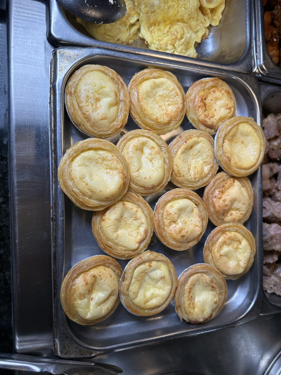 A tray of golden egg tarts in their pastry cases