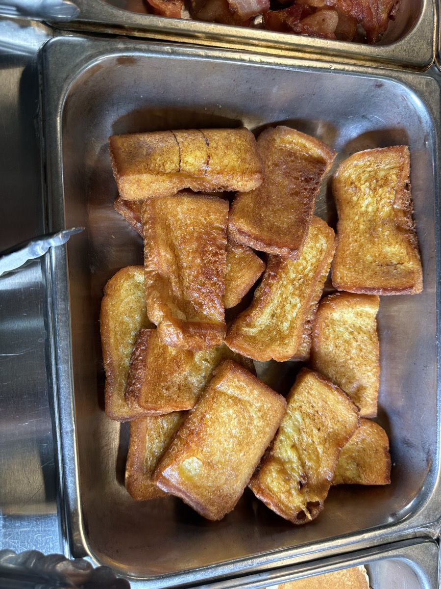 A tray of golden french toast pieces dusted with cinnamon