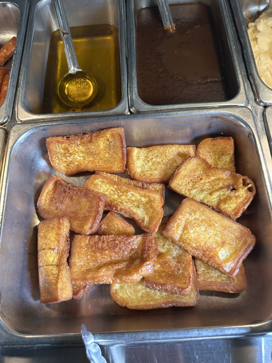 A full serving tray of french toast beside the syrup