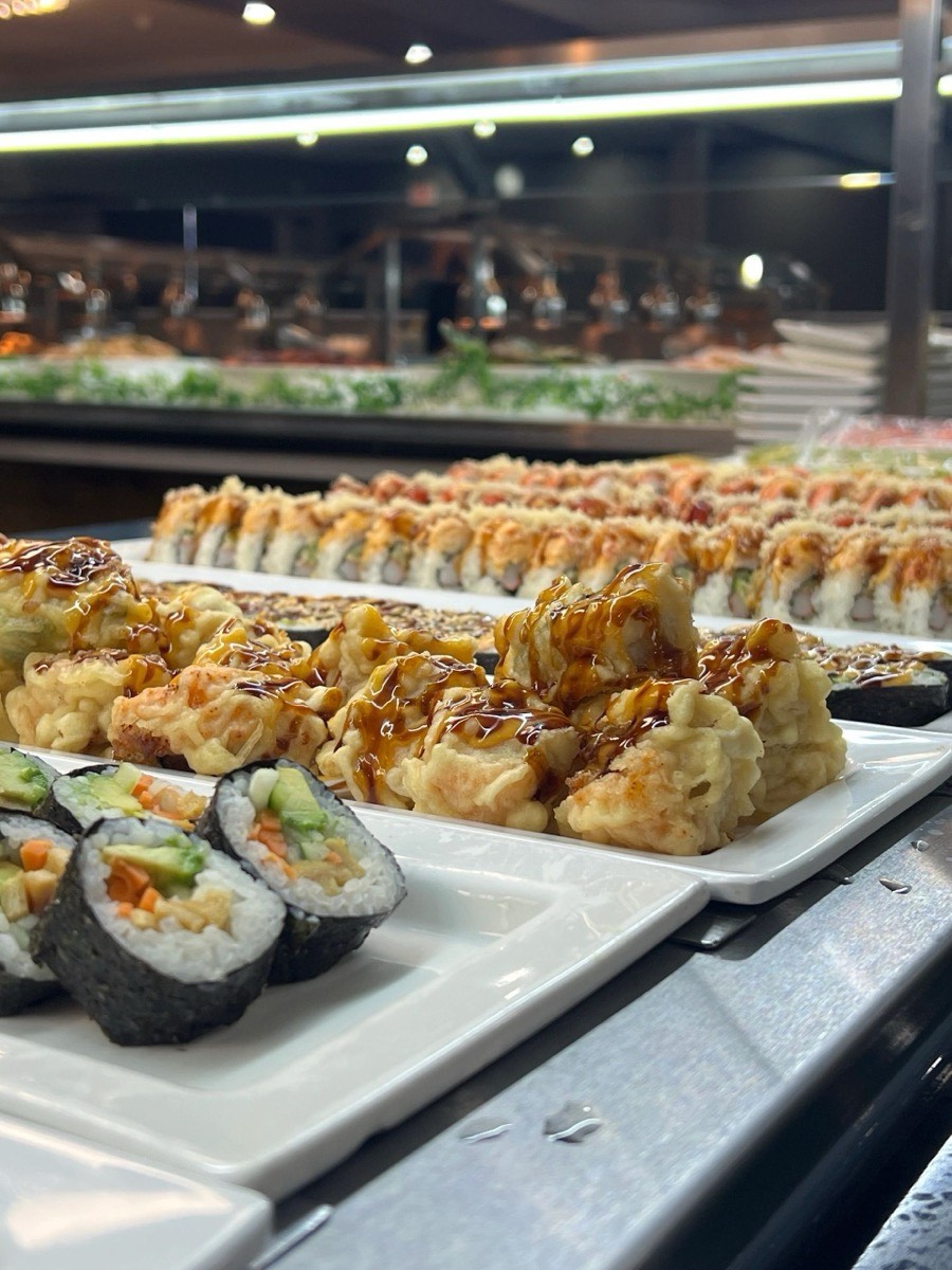 Sushi and tempura at the counter. Trays of sushi rolls and tempura along the buffet line at Jade Asian Buffet