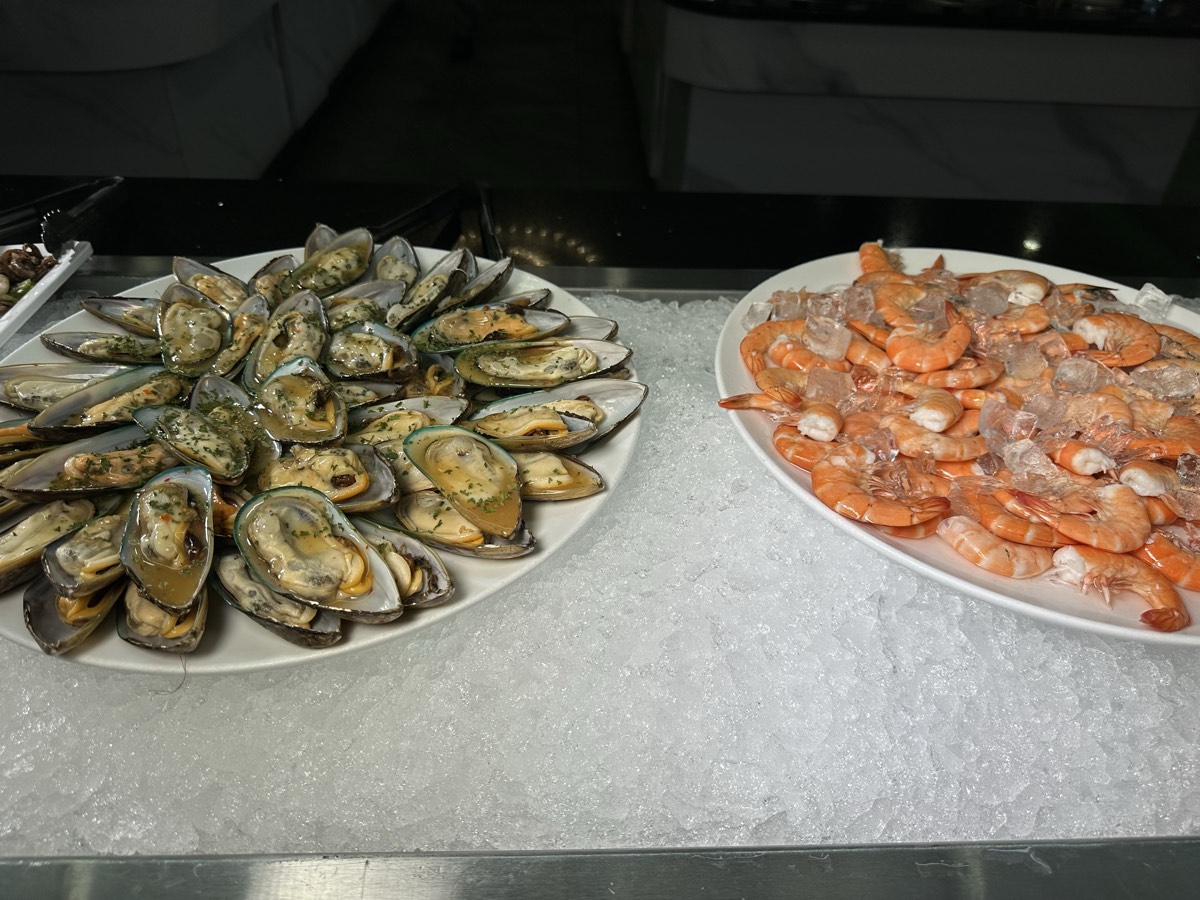 Plates of green-lipped mussels and chilled shrimp resting on crushed ice