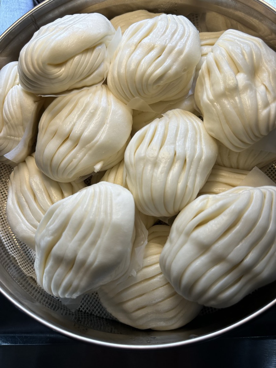 A steamer filled with pleated white steamed buns