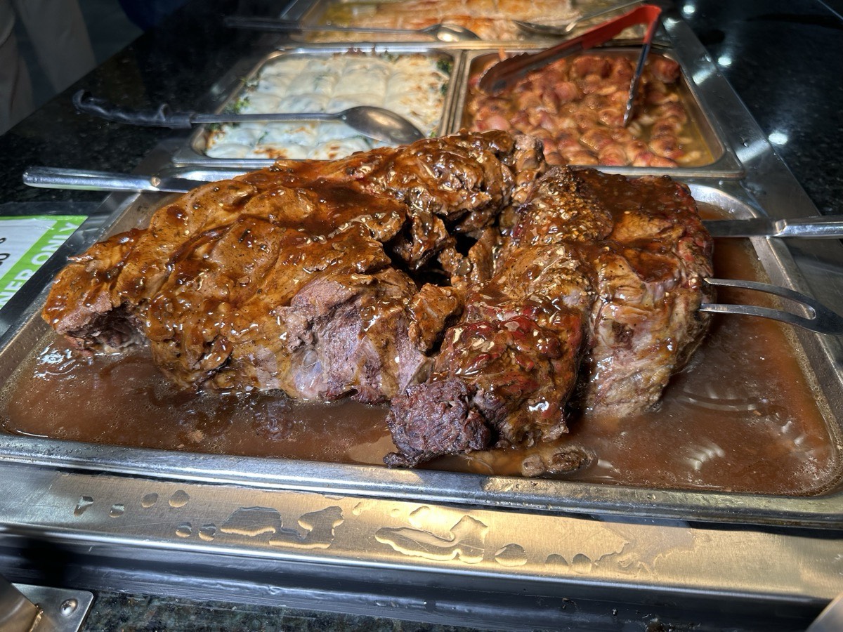 A roast beef joint resting in its juices in a carving tray
