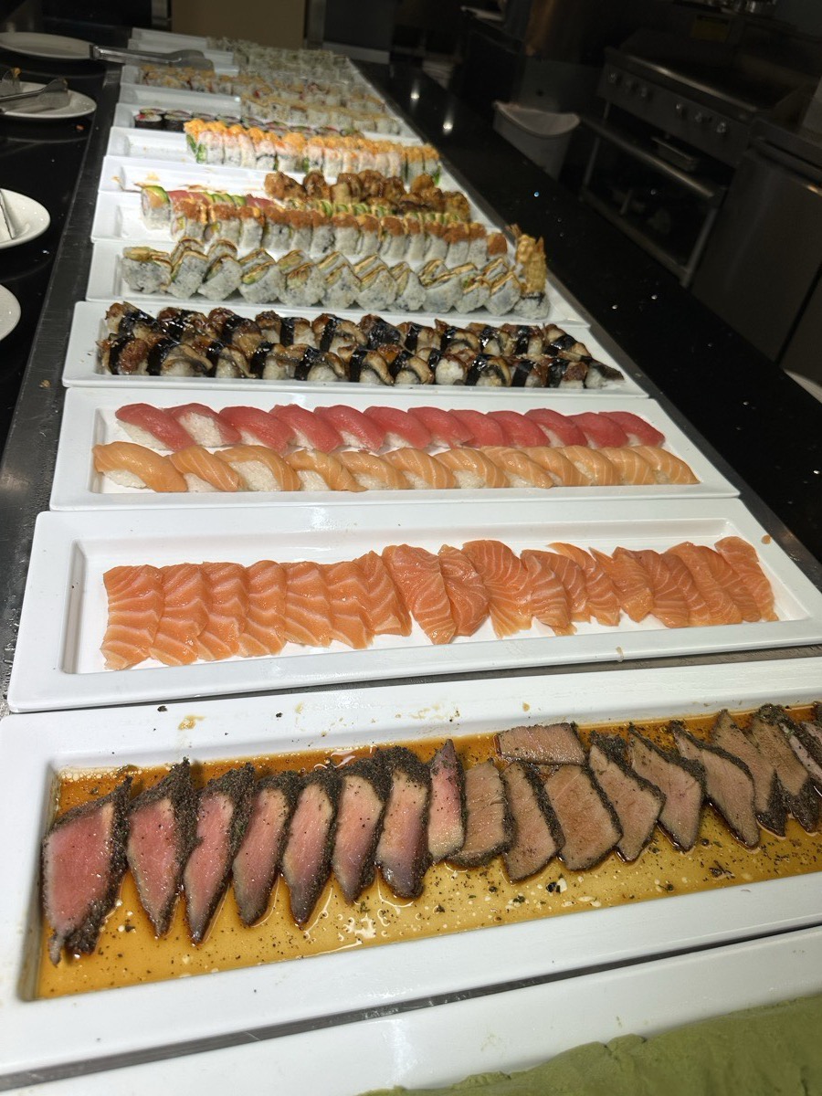 Rows of sliced sashimi and nigiri arranged on white platters