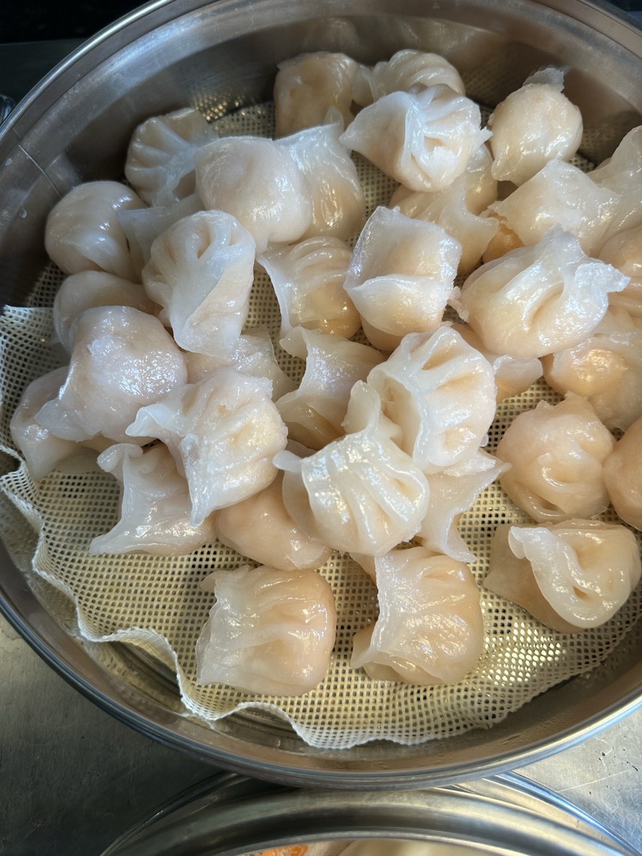 Translucent steamed dumplings and pleated shumai in a steamer basket