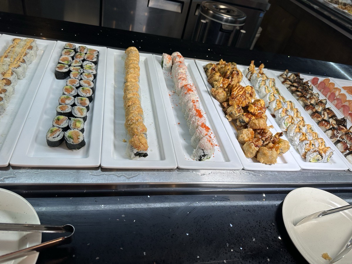 Trays of sushi rolls beside golden tempura pieces