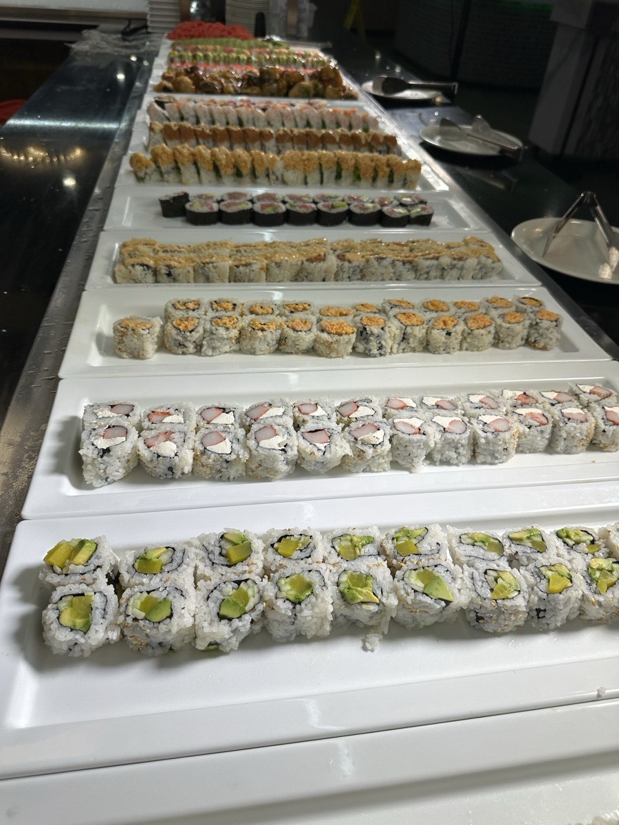 Rows of avocado and speciality sushi rolls running down the buffet line